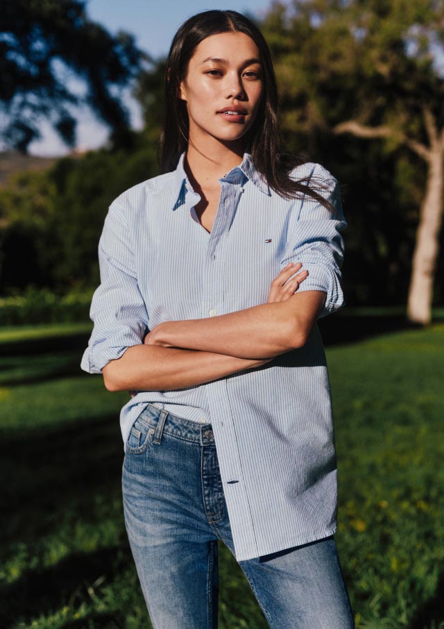 A male model wears an Oxford shirt and shorts, new from Tommy Hilfiger.