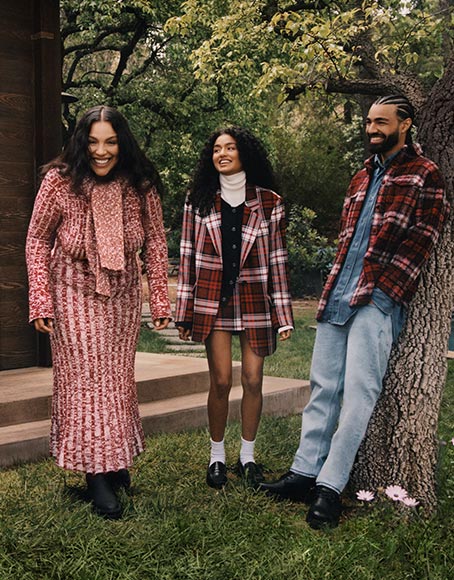 Two female models and one male model each wear tartan-themed apparel and accessories, new from Tommy Hilfiger.