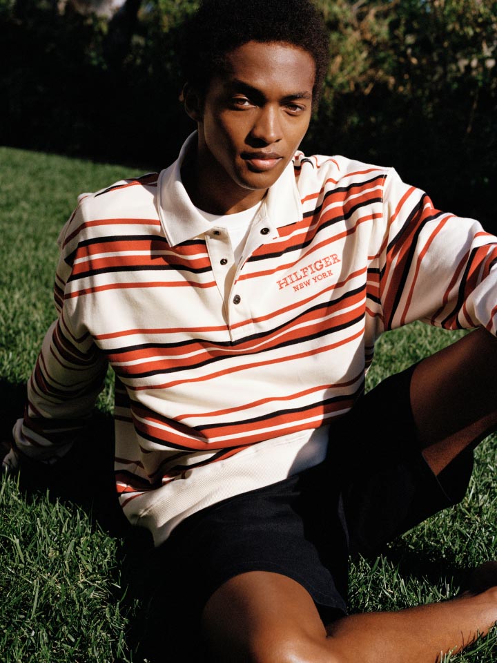 A male model wears a rugby top and shorts, new from Tommy Hilfiger.