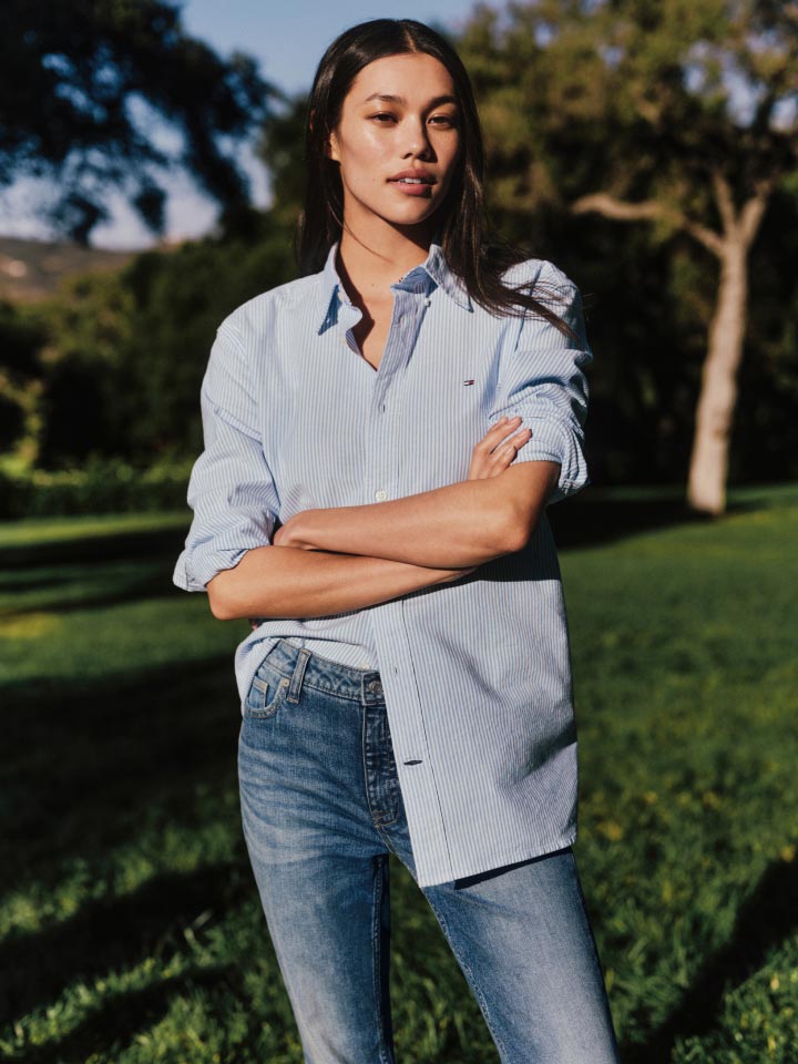 A female model wears an Oxford shirt and jeans, new from Tommy Hilfiger.