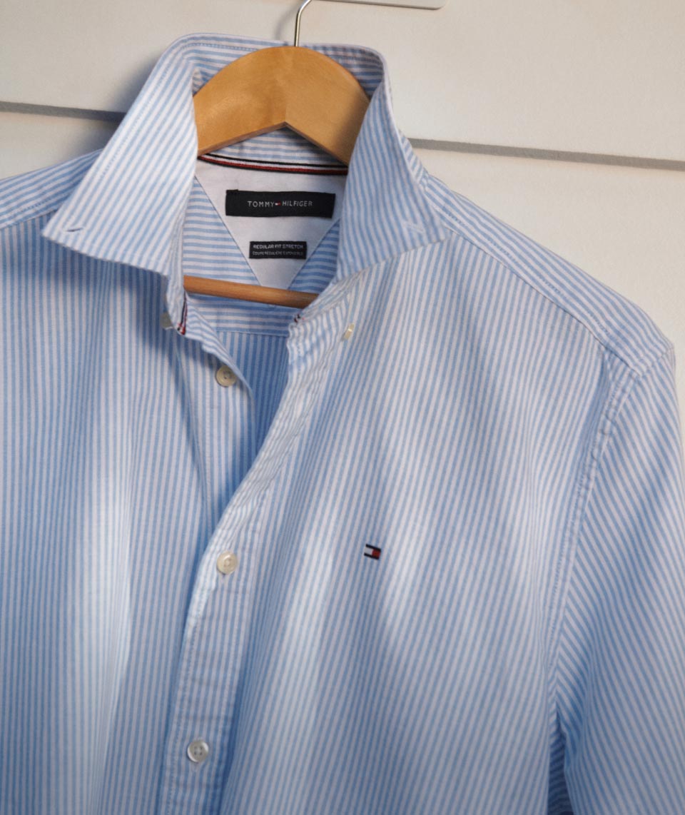 A close-up shot of a striped Tommy Hilfiger oxford shirt, showing details of the collar and buttons.
