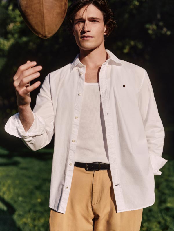 A male model wears an Oxford shirt, new from Tommy Hilfiger.
