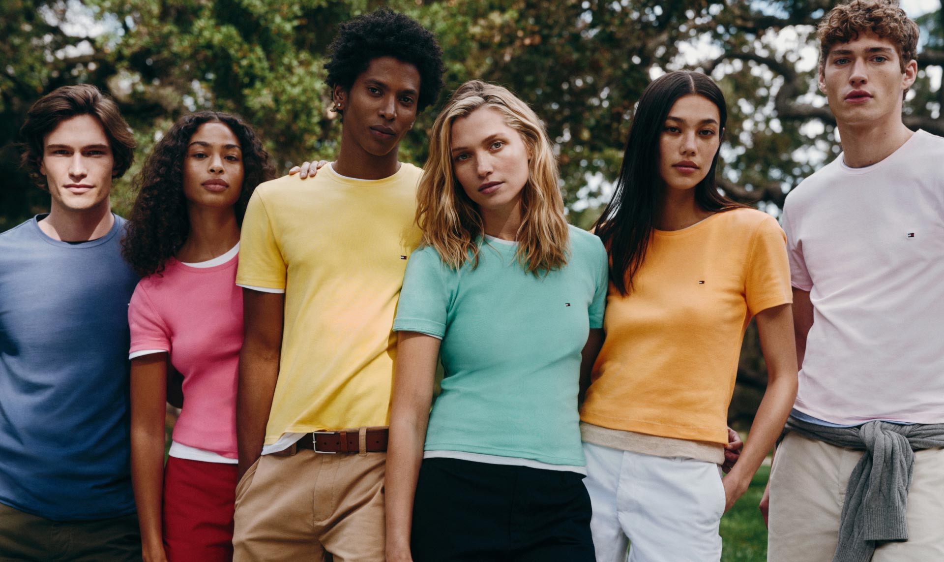 A group of male and female models wear t-shirts in bright colors, new for spring from Tommy Hilfiger.
