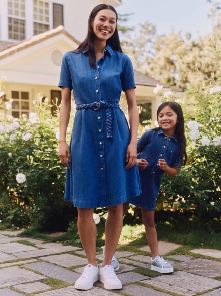 A mother and daughter wear matching denim dresses from Tommy Hilfiger.