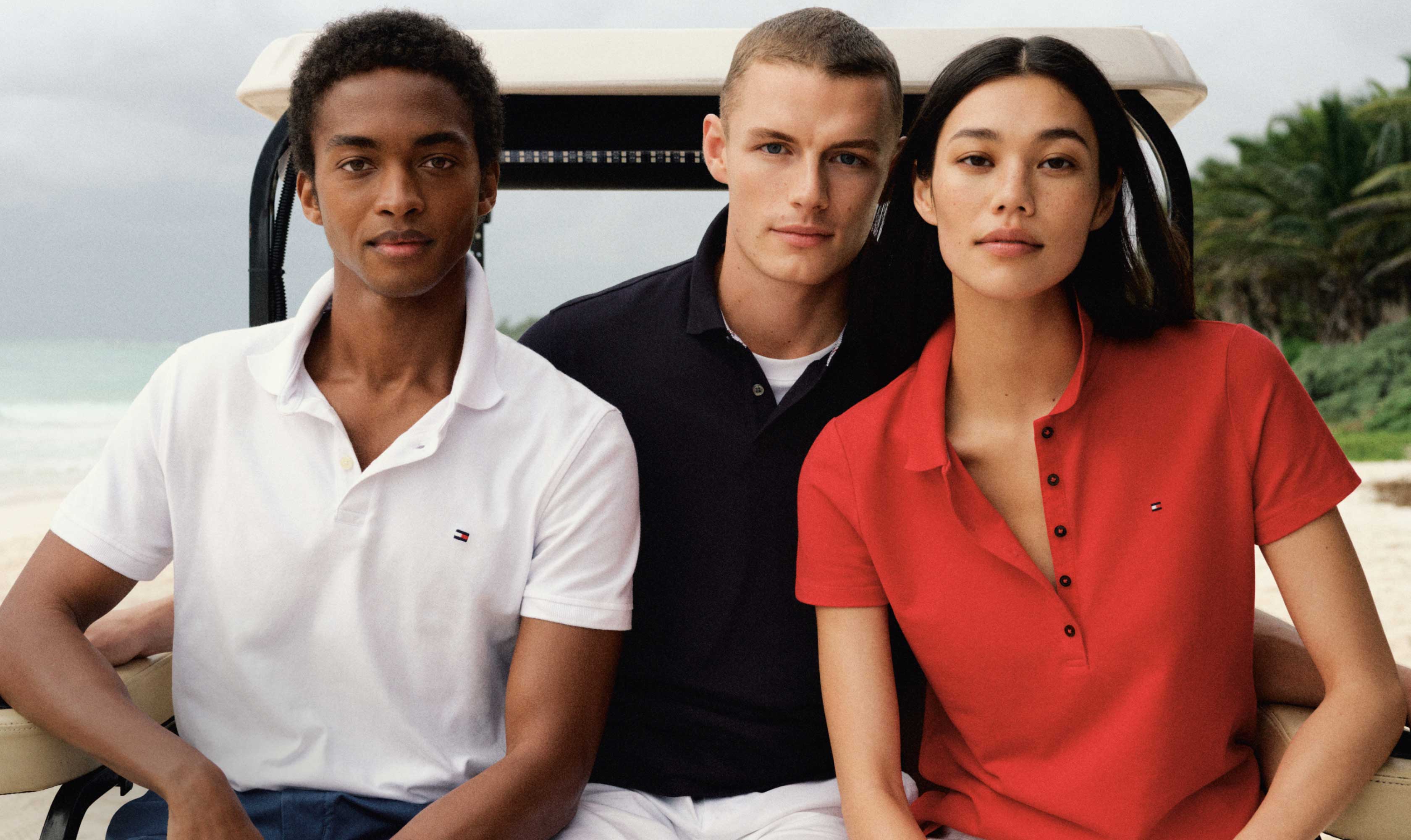 A group of male and female models wear Tommy Hilfiger polos in summer colors.