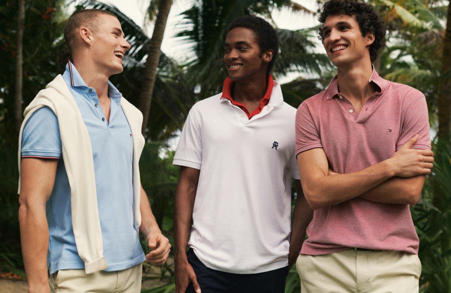 Three male models wear Tommy Hilfiger polos in blue, white and pink.