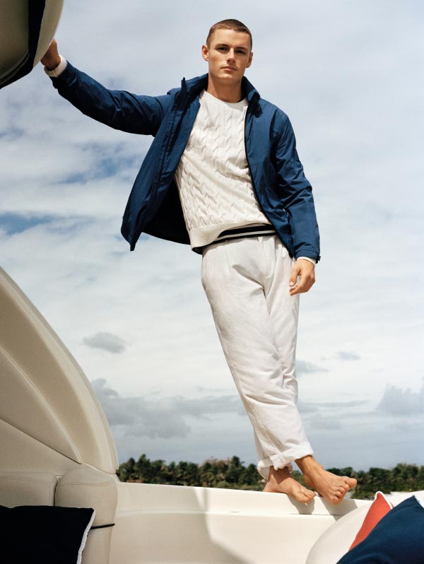 A male model stands on a boat wearing new summer styles from Tommy Hilfiger.