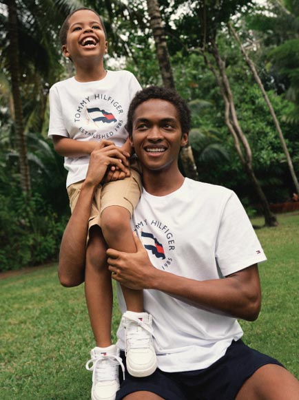 A father and son wear matching t-shirts from Tommy Hilfiger.