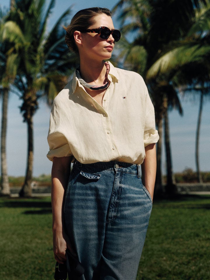 Woman wearing Tommy Hilfiger linen shirt and jeans standing on the sidewalk