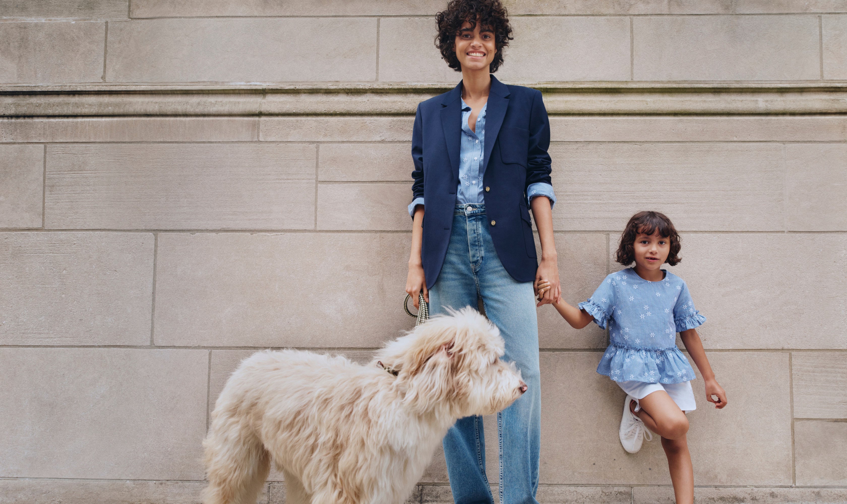 Woman and girl standing on a wall with dog dressed in Tommy Hilfiger