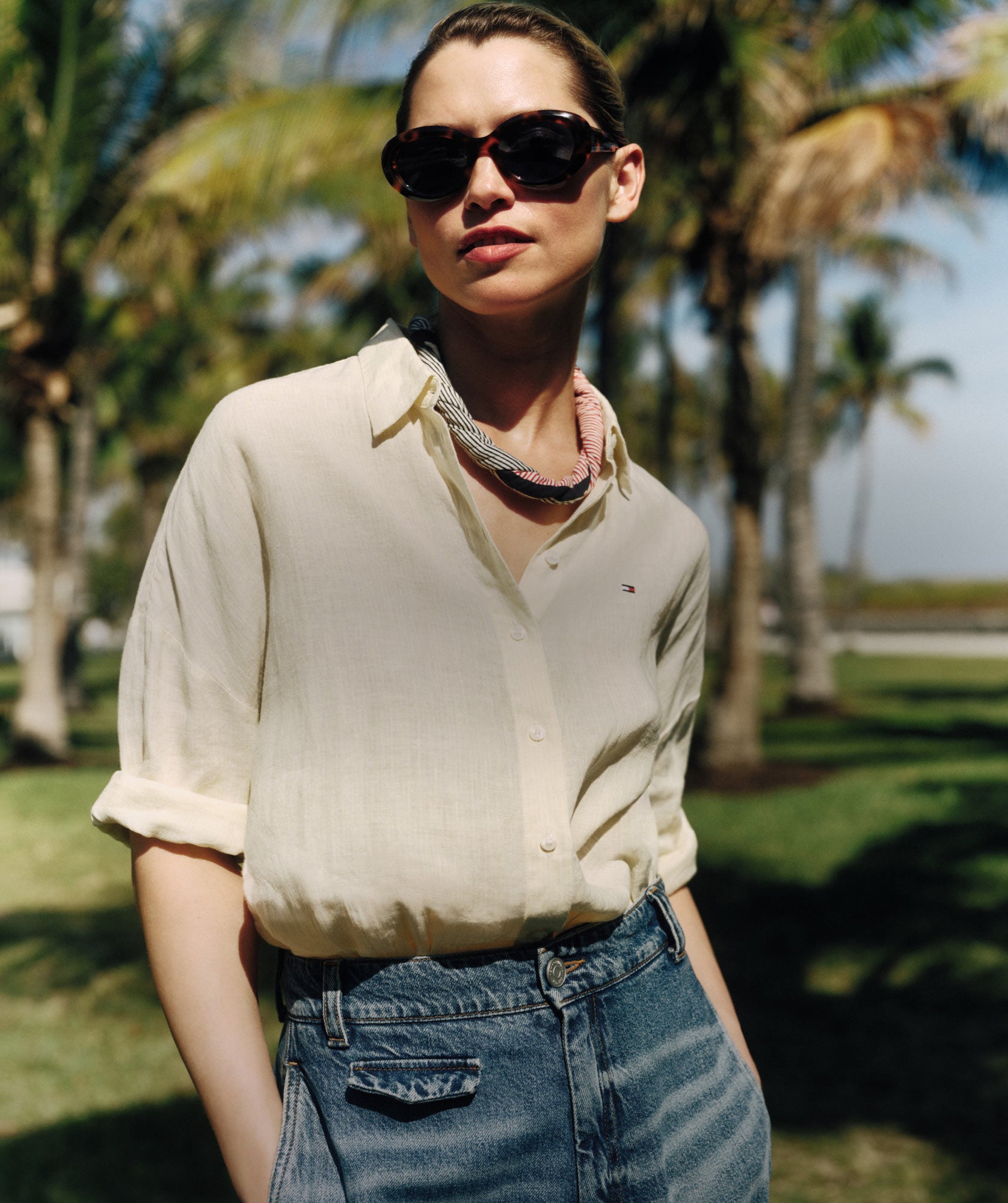 Woman wearing Tommy Hilfiger lienen button down tucked into jeans with sunglasses
