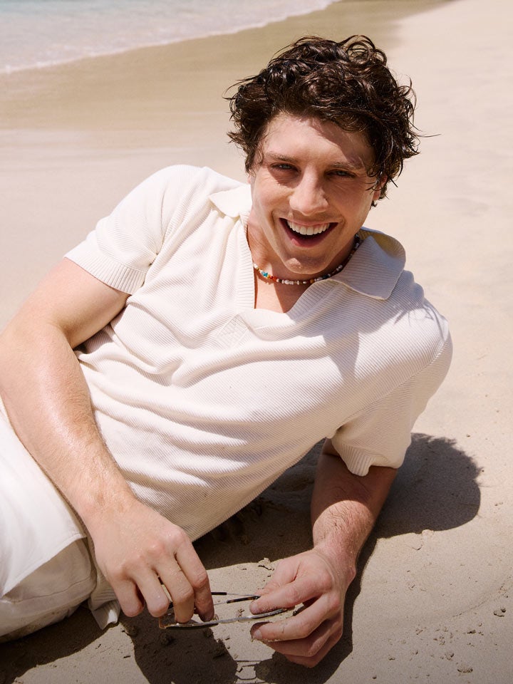 Homme allongé sur la plage, portant un polo et un chino Tommy Hilfiger