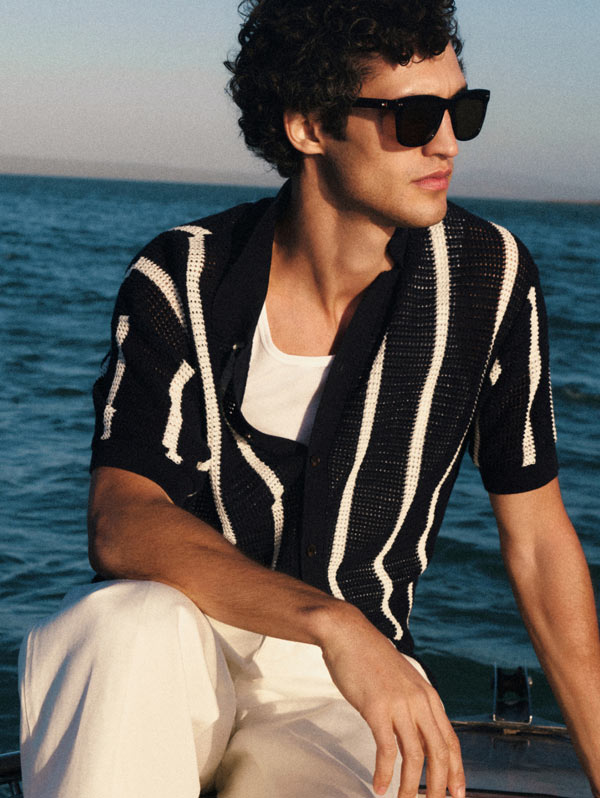 Man wearing Tommy Hilfiger knit polo and sunglasses looking in the distance