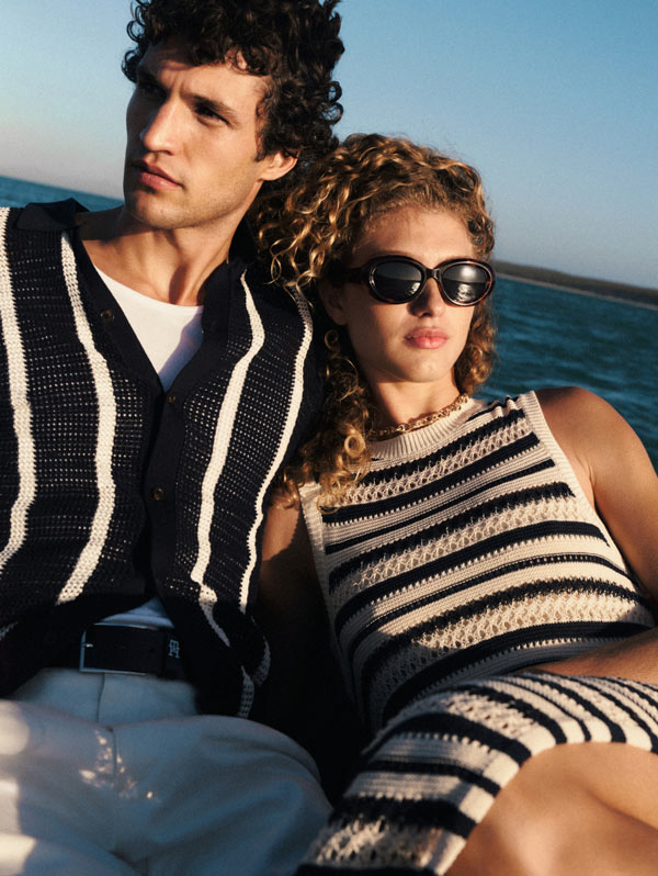 Woman leaning on man in Tommy Hilfiger knit polo while on a boat dressed in Tommy hilfiger stripped dress