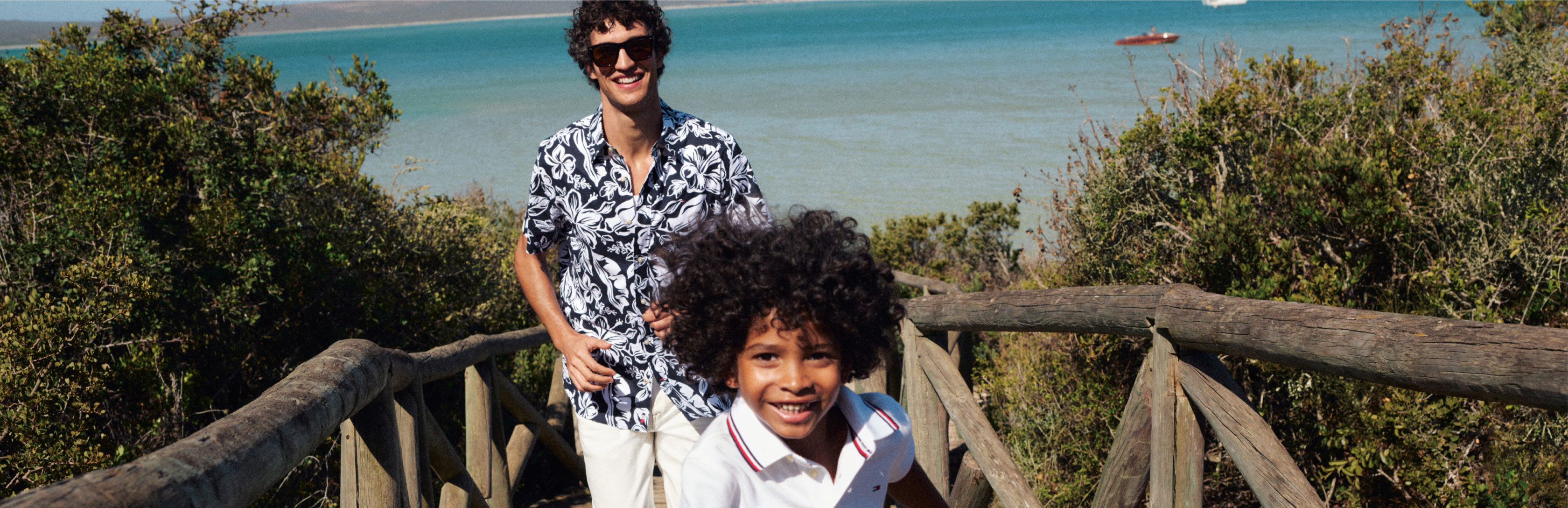 Man and boy walking up from the beach wearing tommy Hilfiger warm weather essentials