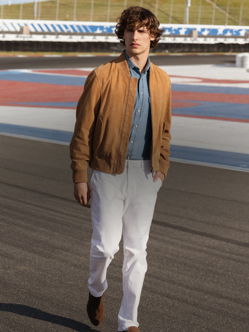 Man walking down the racetrack dressed in Tommy Hilfiger race jacket and and straight fit pants