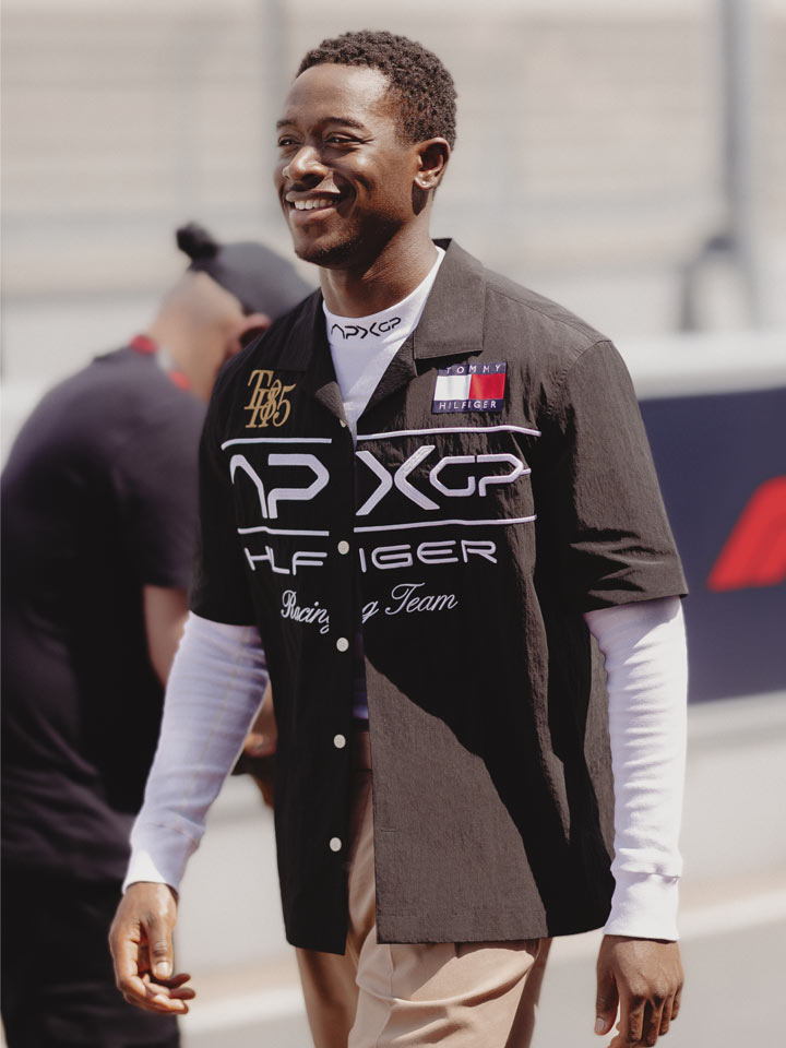 Damson Idris wearing black APXGP oversized polo walking down the track
