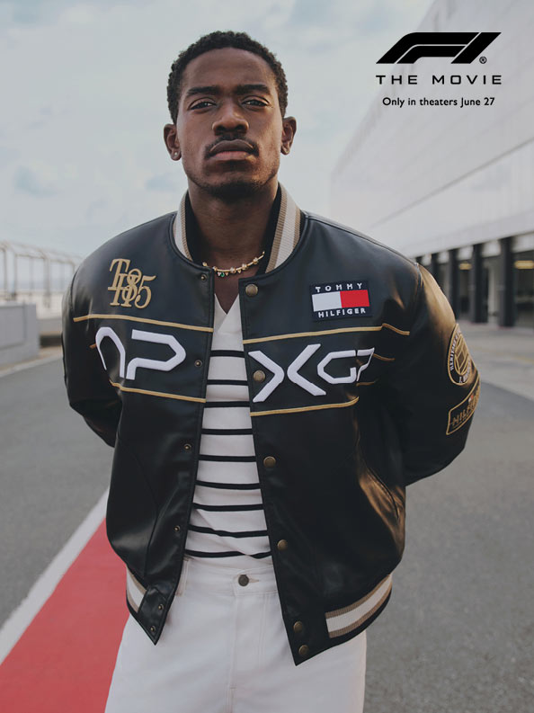 Damson Idris standing on the ractrack wearing black APXGP racing jacket