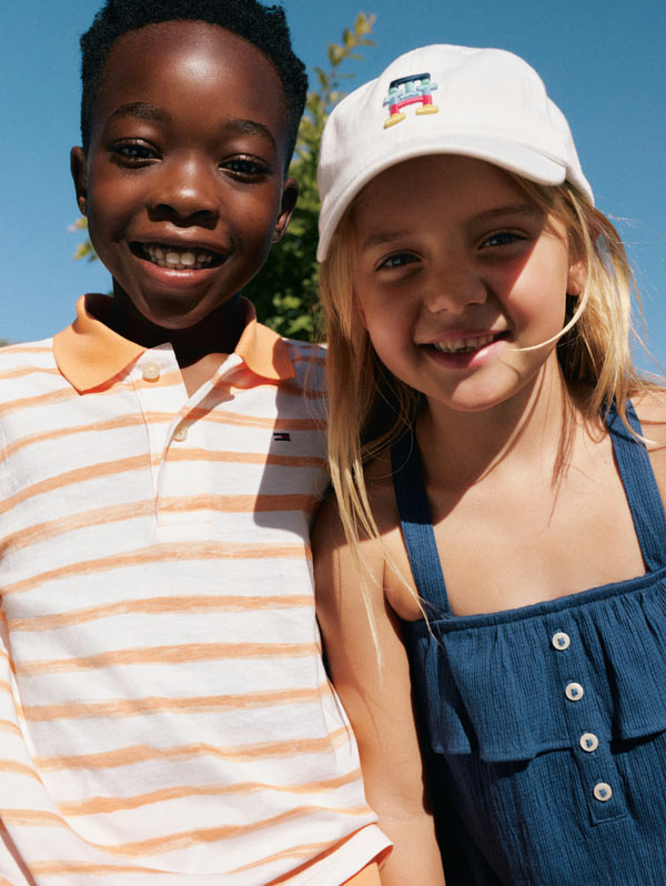 Kids looking into camera dressed in Tommy Hilfiger polo and dress