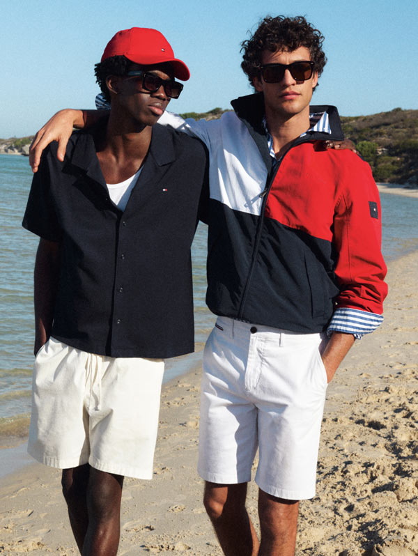 Two guys on the beach dresed in Tommy Hilfiger with arms around each other