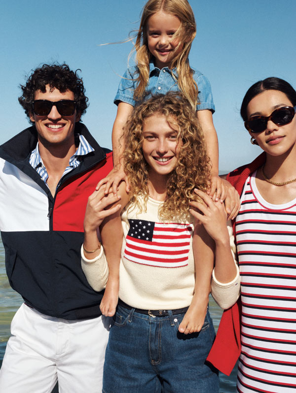 Family on the beach with little girl on woman shoulders all dressed in Tommy Hilfiger