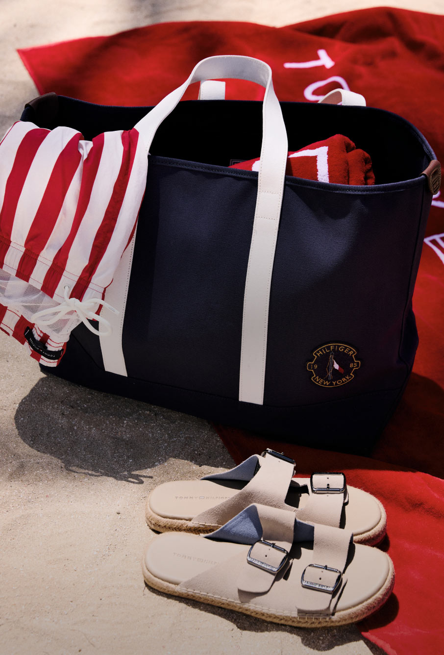 Tommy Hilfiger tote bag on the beach next to a pair of sandals