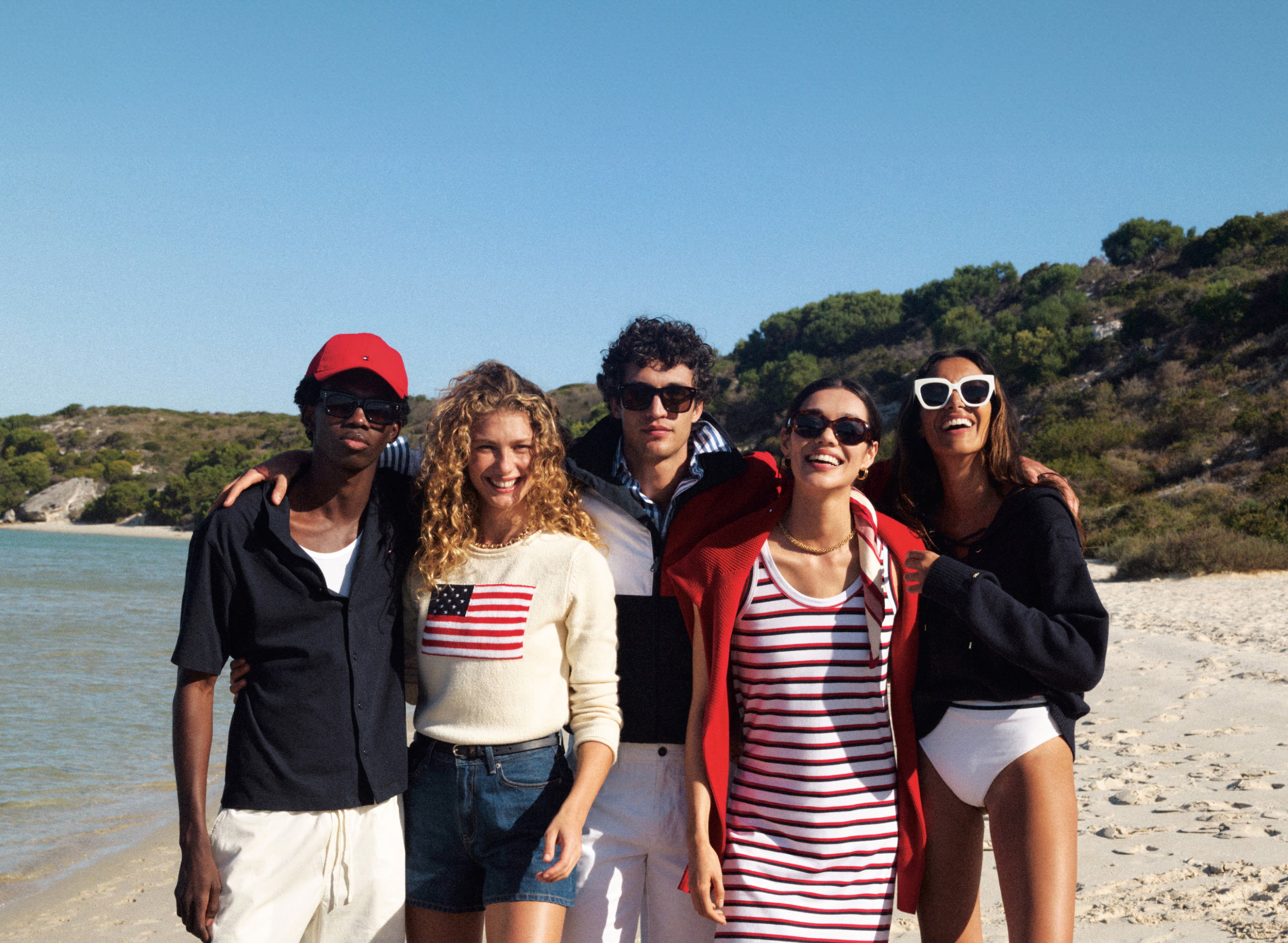 Group on a beach near the water dressed in classic Tommy Hilfiger red white and blue