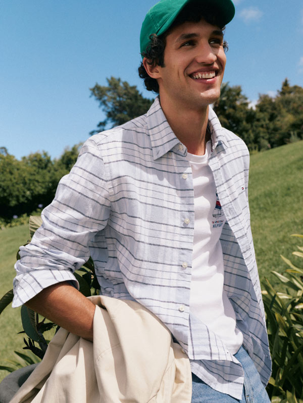 Man smiling wearing a hat with Tommy Hilfiger button down with tshirt underneath