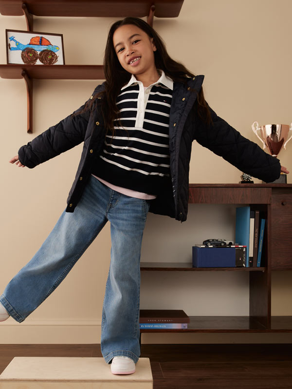 A little girl standing in a room wearing Tommy Hilfiger