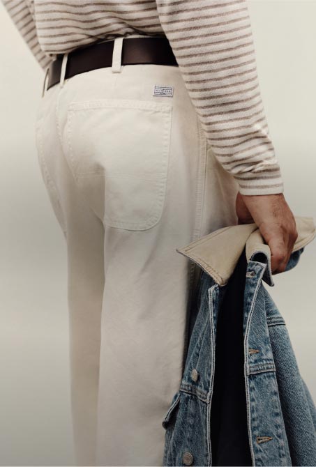 A men standing wearing a Tommy Hilfiger pants and carrying a denim jacket