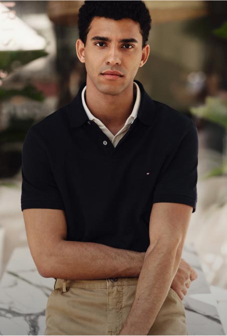 A man sitting wearing a Tommy Hilfiger black polo