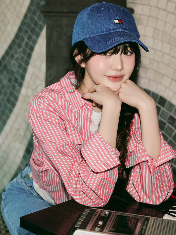 Won Young sitting on subway stairs in a red striped Tommy Hilfiger button-down shirt, blue jeans, and a blue baseball cap.