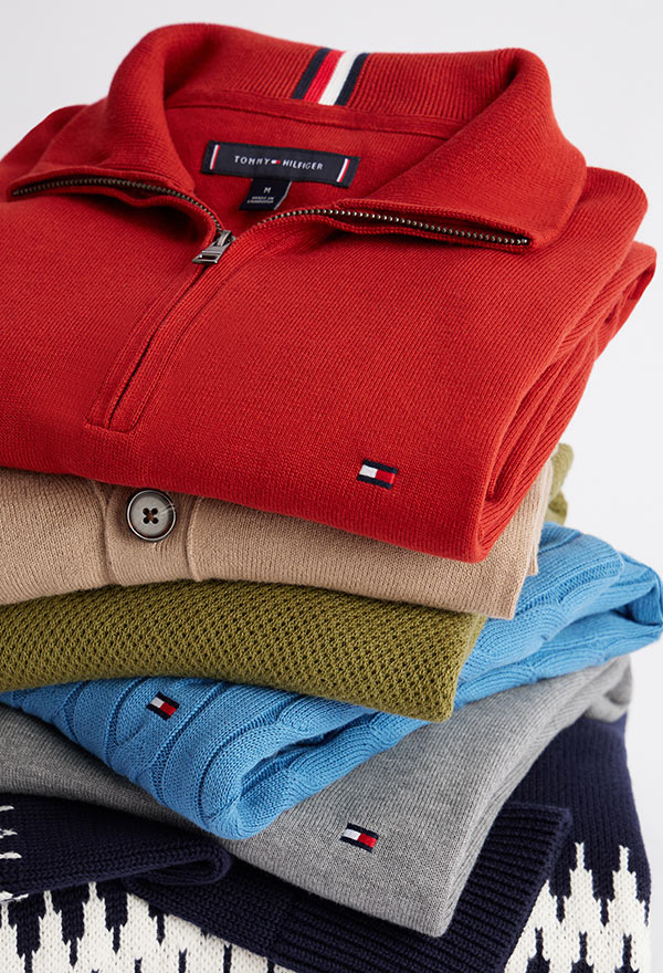 Clothing rack featuring Tommy Hilfiger men's outerwear, including wool coats, puffers, quilted jackets, and down parkas in neutral and navy tones.
