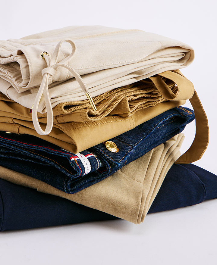 Stack of folded Tommy Hilfiger women's jeans in various washes and styles, showcasing logo details and back patch branding.