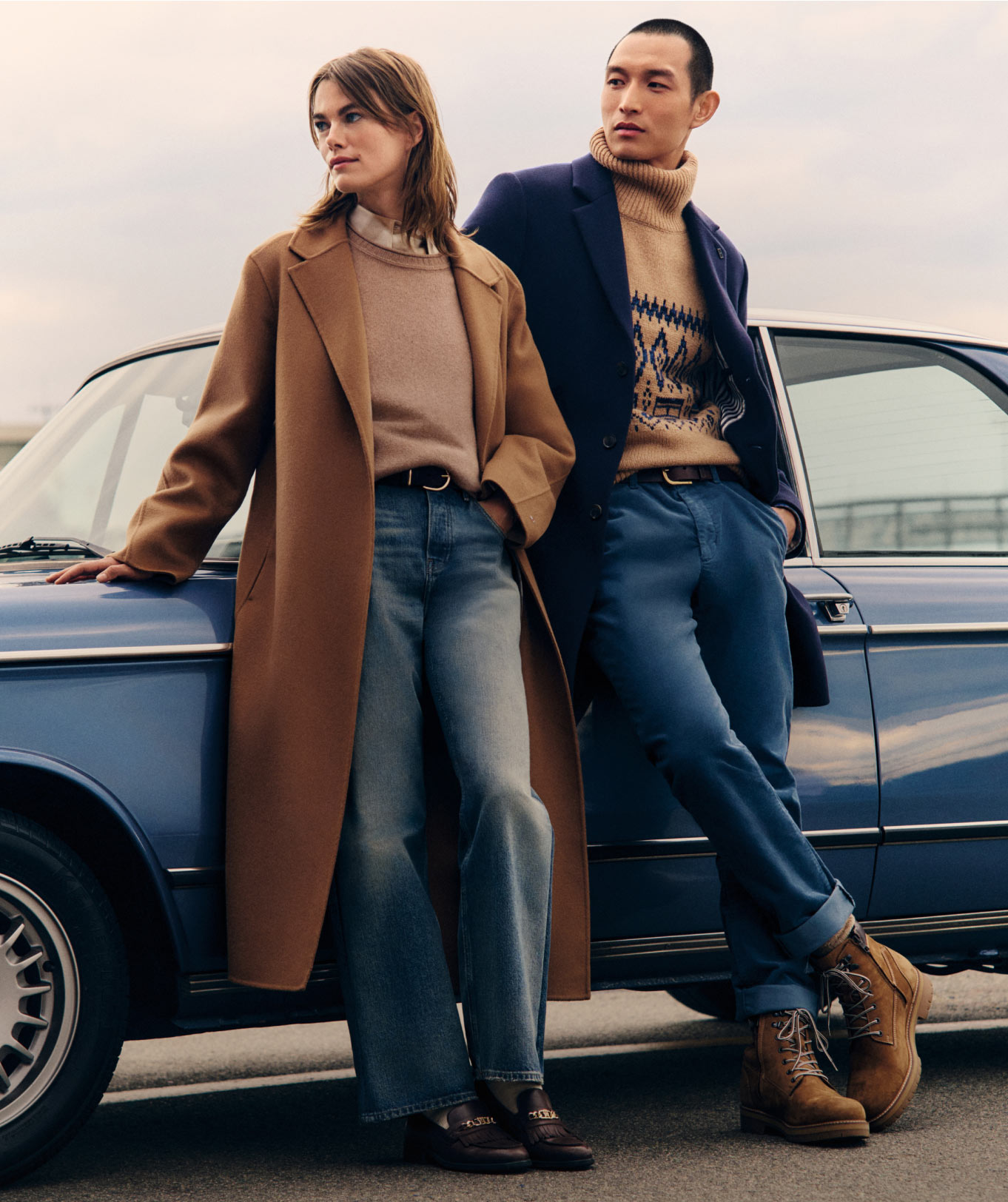 Two models wearing Tommy Hilfiger denim outfits and layered outerwear, standing in front of a vintage blue car.