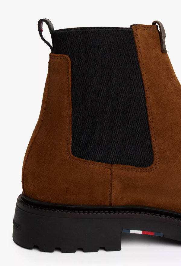 Close-up of a brown suede Tommy Hilfiger Chelsea boot featuring a black elastic side panel and lug sole.