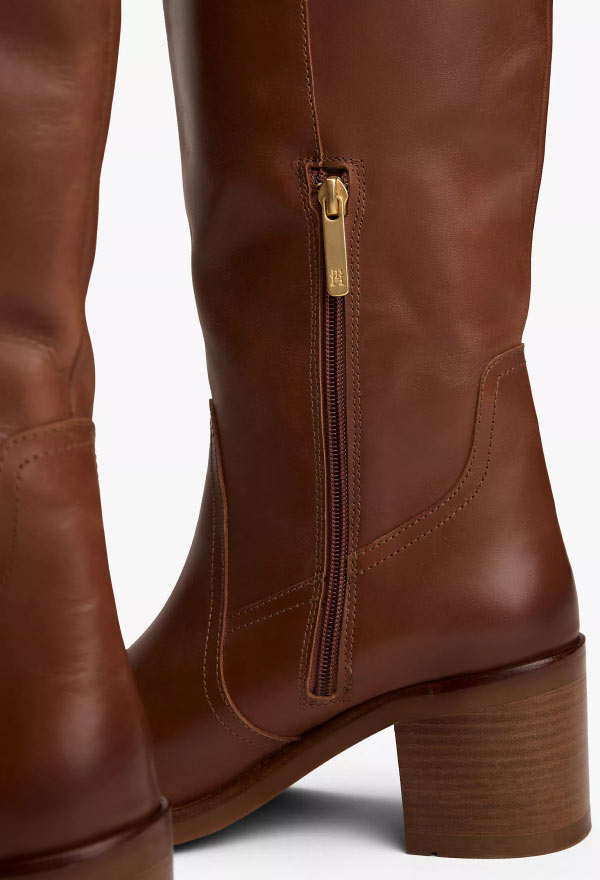 Close-up of a tall brown leather Tommy Hilfiger boot featuring a side zipper and stacked heel.