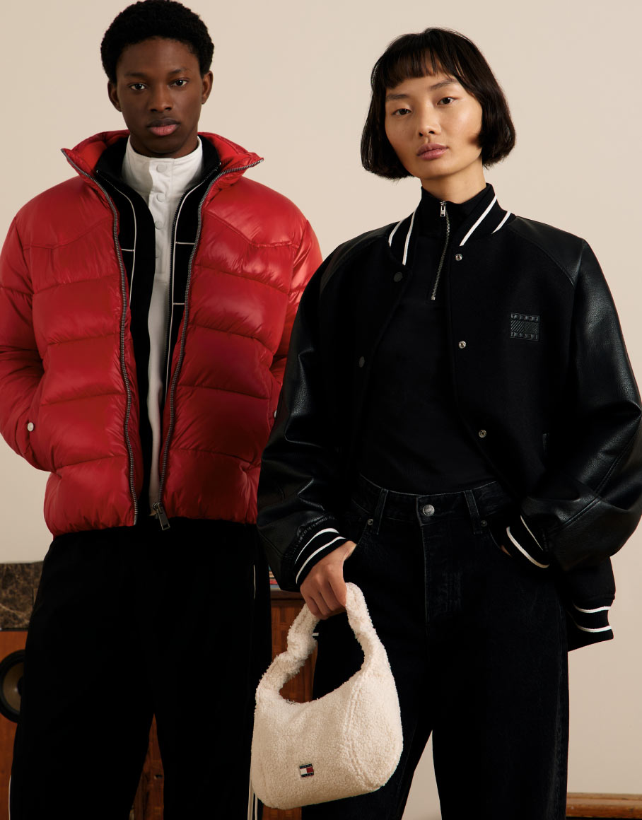 Two models in striped Tommy Hilfiger rugby shirts and jeans standing against a neutral backdrop.