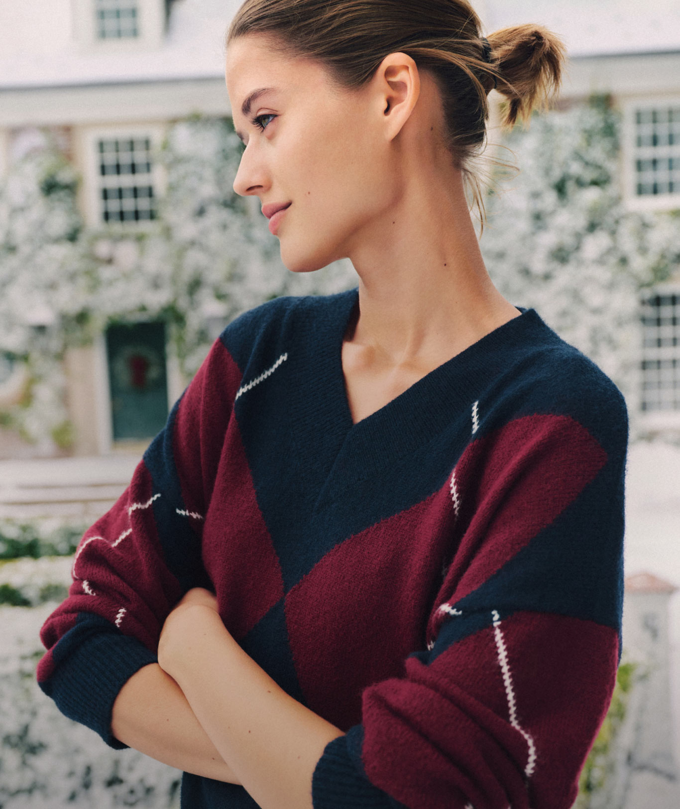 Group of models outdoors in Tommy Hilfiger novelty sweaters—plaid, argyle, and intarsia—chatting on a winter street.