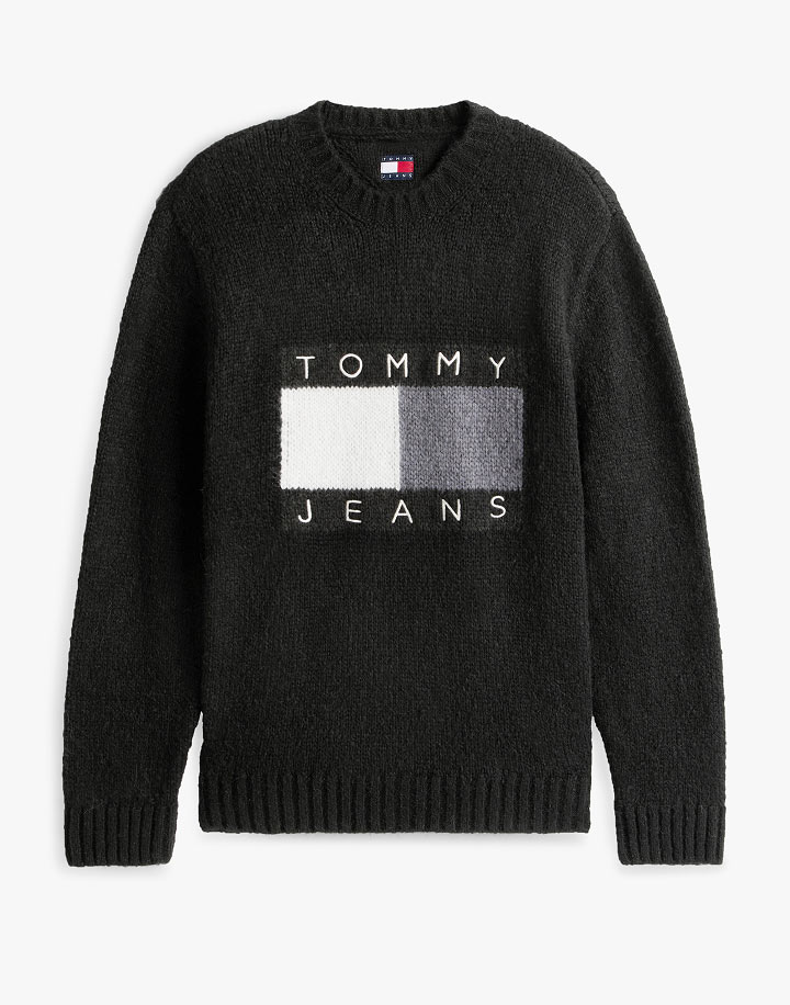 Black Tommy Jeans crewneck sweater with a centered flag logo, flat lay on white.