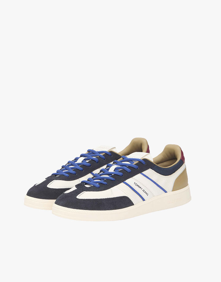 Blue and white Tommy Jeans low-top sneakers with contrast overlays and a cream sole, shown on white.
