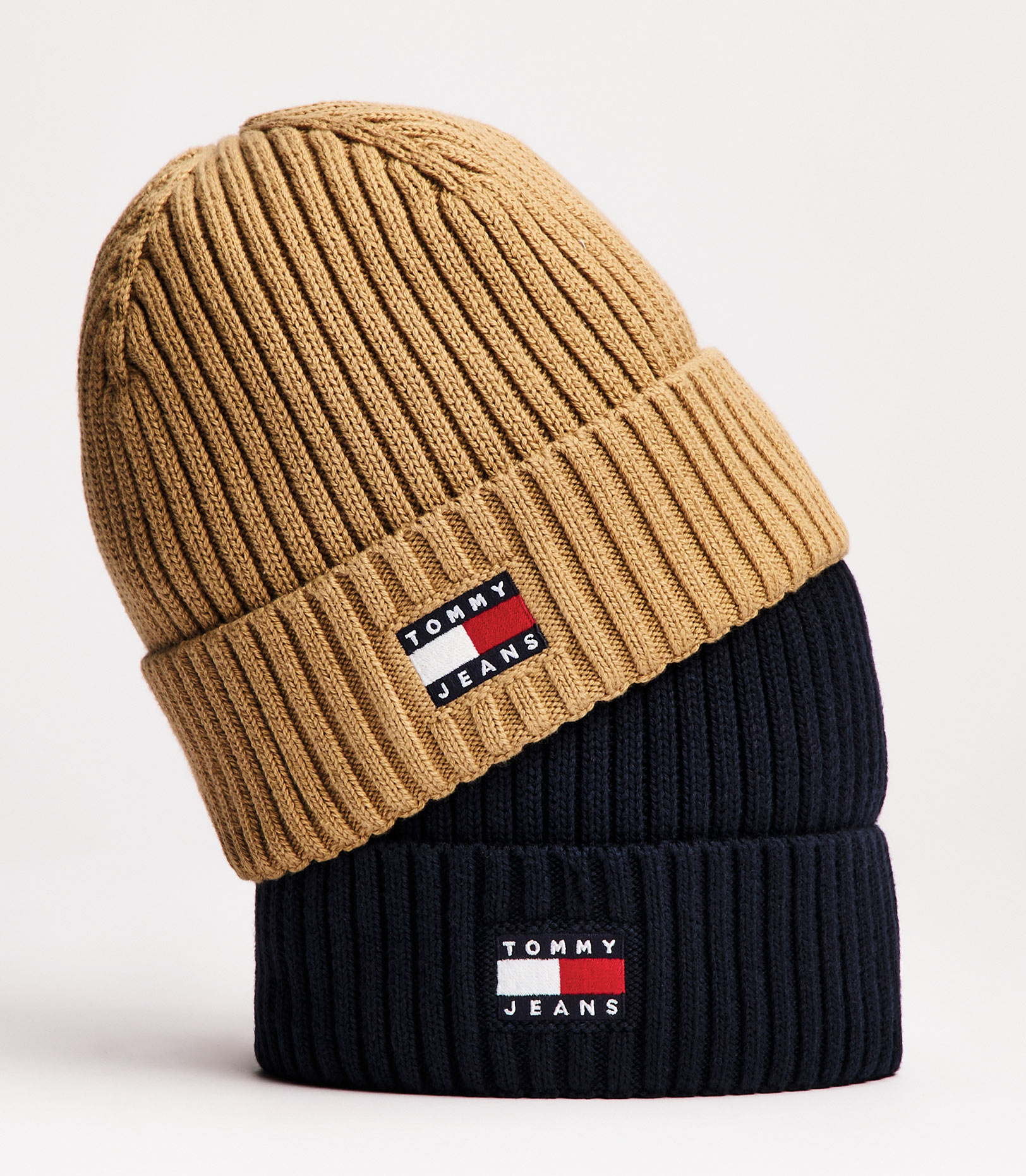 Ribbed Tommy Jeans beanie in tan and navy colorblock with a front flag patch, studio shot.