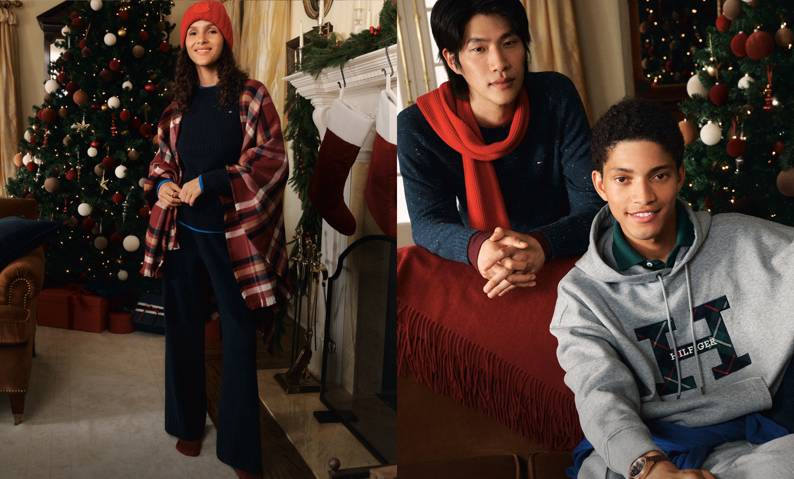 Models in a cozy home setting with a Christmas tree wearing Tommy Hilfiger loungewear: one in a grey logo hoodie, another in a navy sweater with a red scarf, and a third in a red-and-navy plaid shacket over a dark set with a red beanie.
