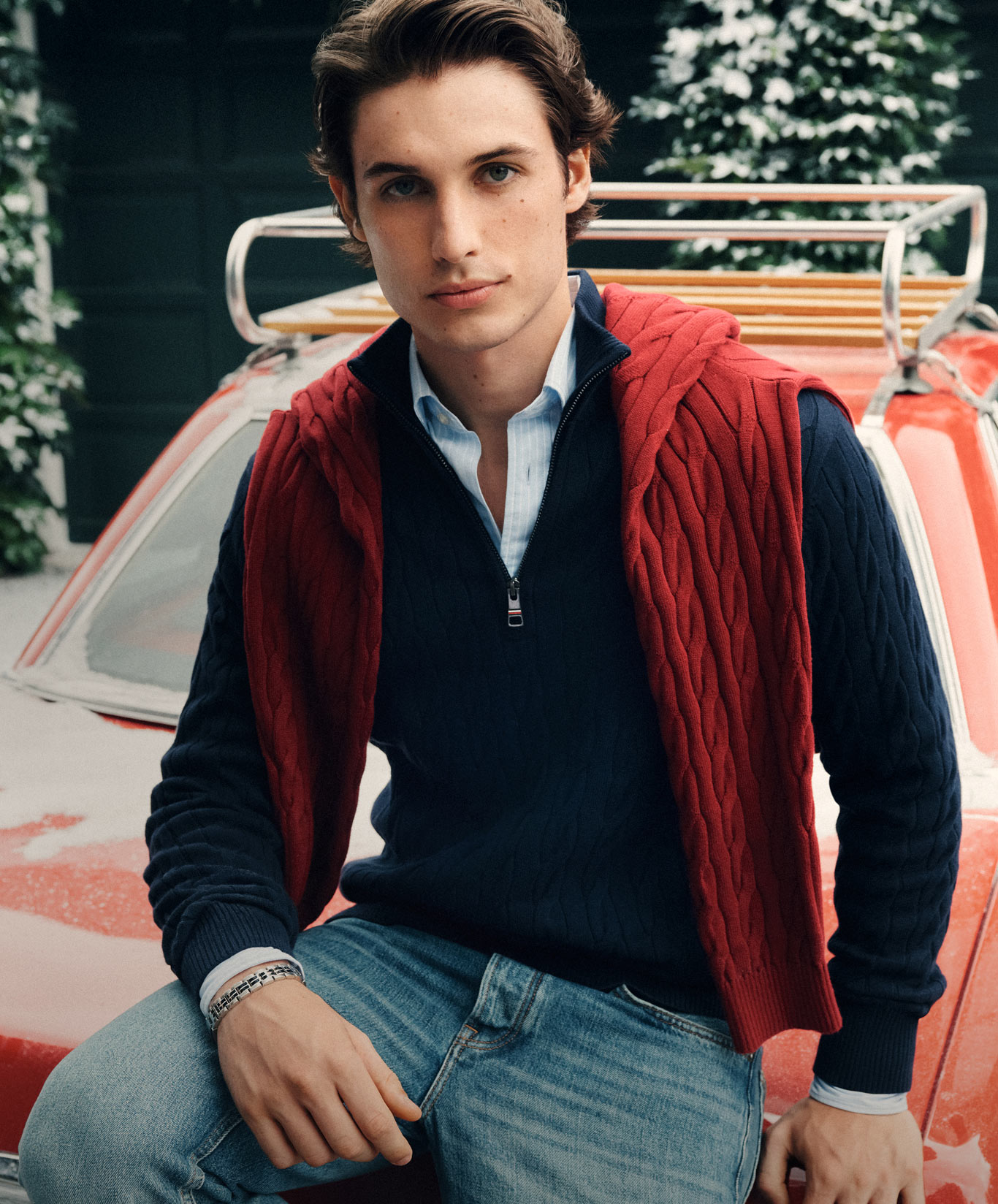 Model in a navy Tommy Hilfiger sweater layered over a button-down with a red quilted vest.