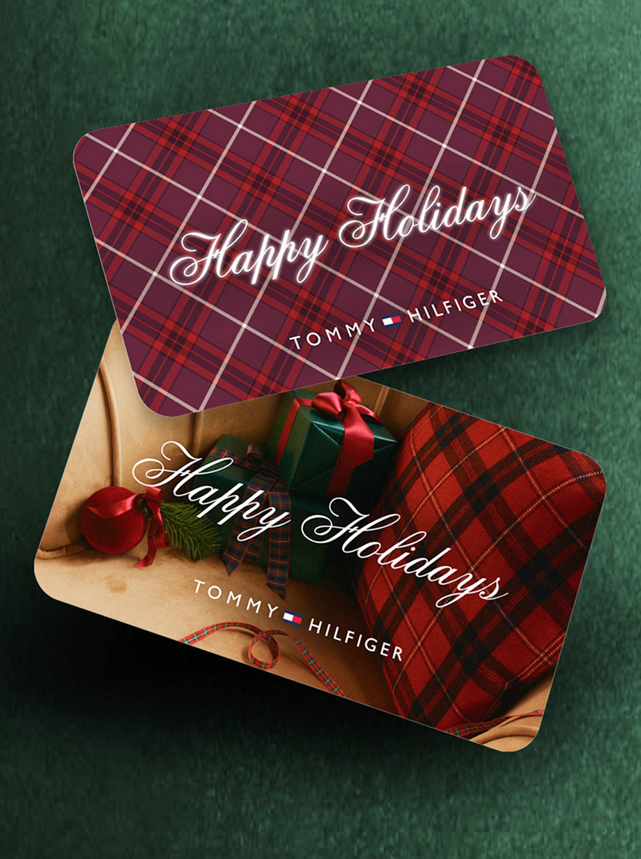 Two Tommy Hilfiger holiday gift cards with red plaid designs and “Happy Holidays” script lettering, arranged on a dark green background.