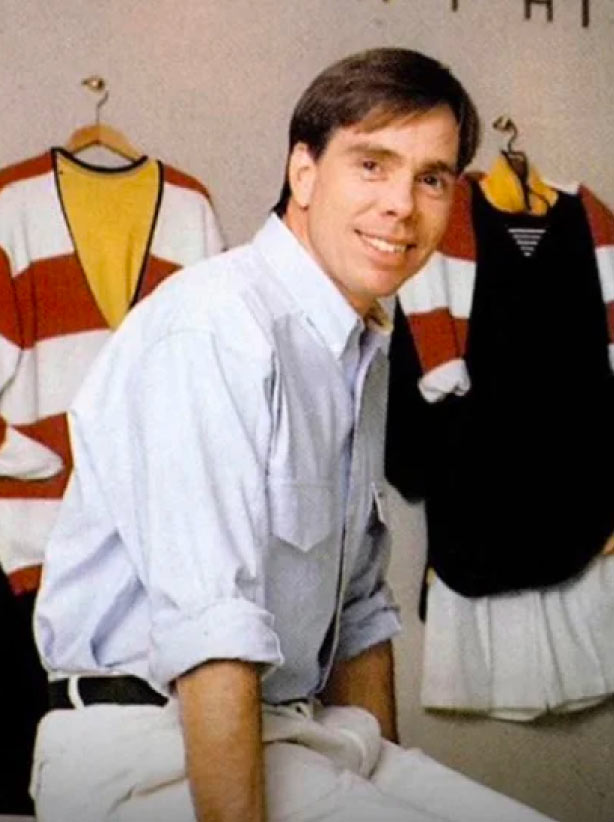 Tommy Hilfiger sitting in front of his outfit designs.