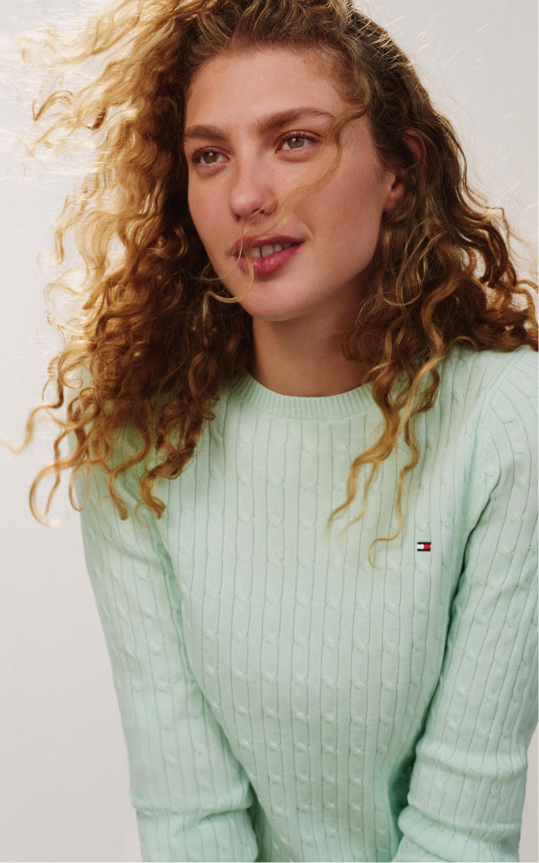 Folded Tommy Hilfiger tops in red and white on a chair, with branded logo taping detail visible across the fabric.
