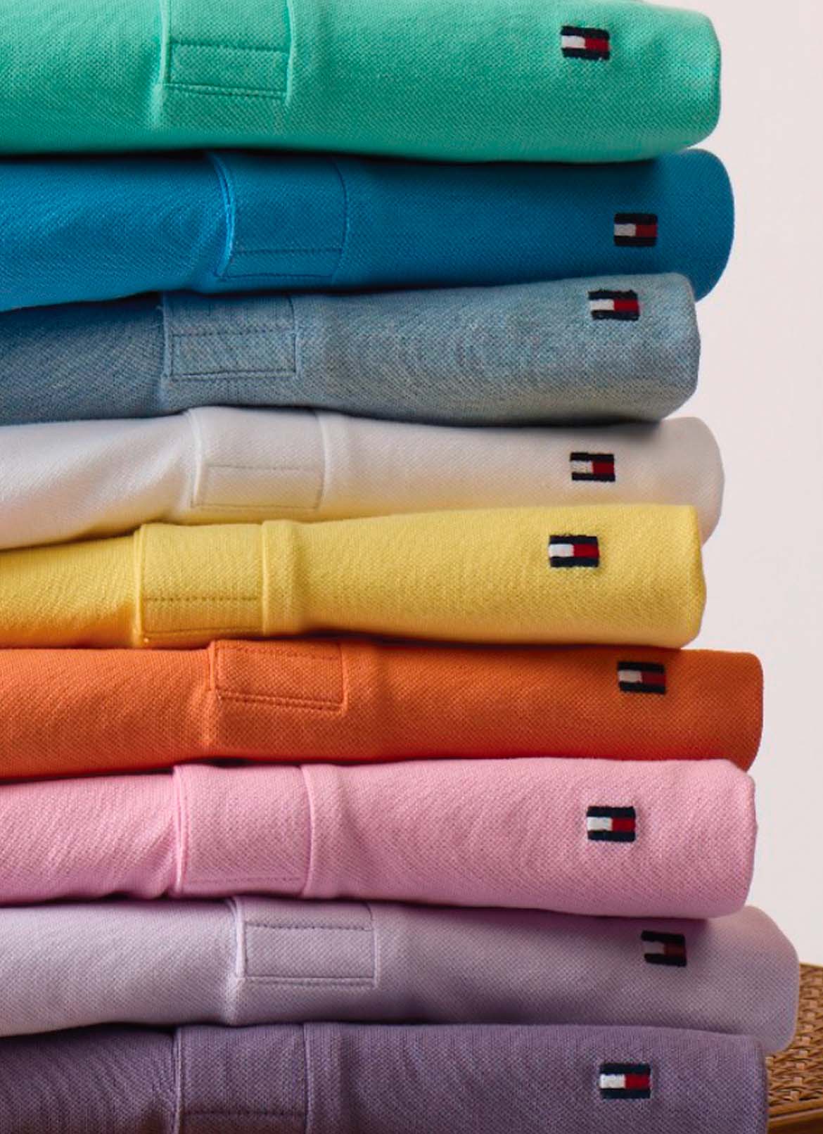 Tommy Hilfiger polos in green, blue, yellow, pink, and purple tones in a studio setting.