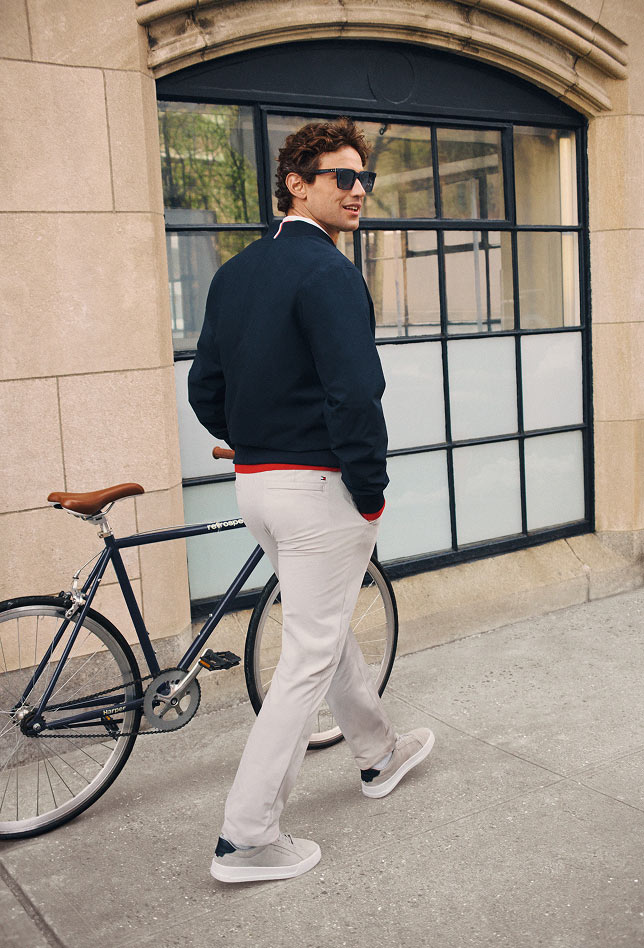 Model outdoors in casual Tommy Hilfiger looks, including a navy sweater with light pants.