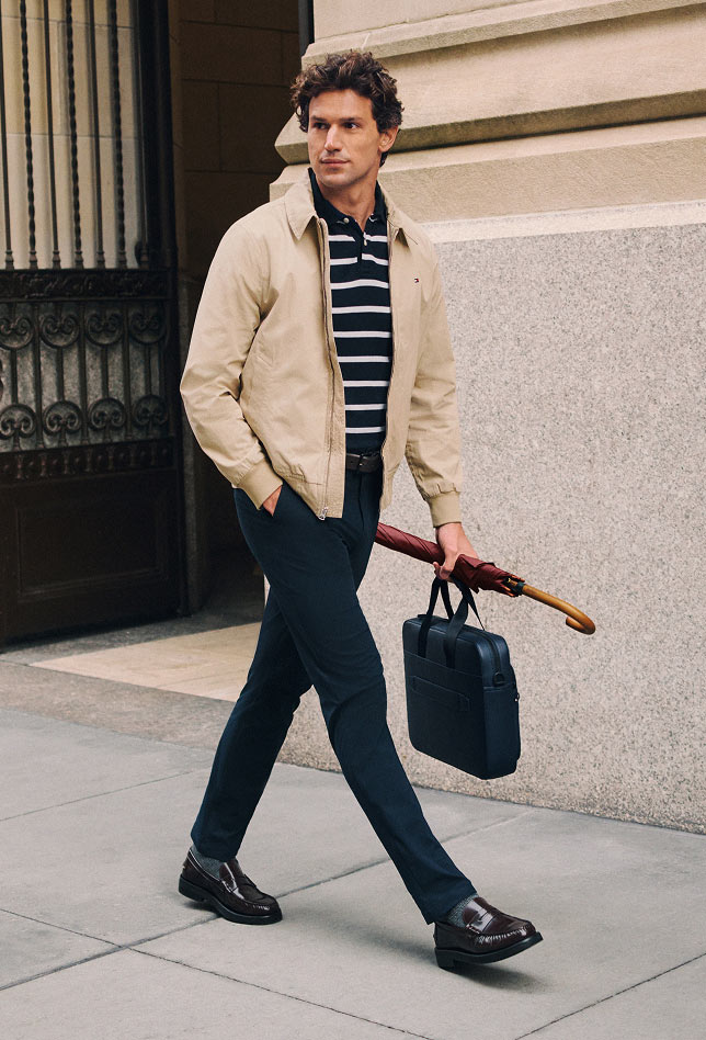 Model outdoors in casual Tommy Hilfiger looks, including a navy sweater with light pants.